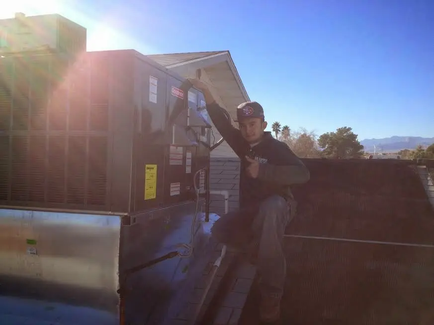 HVAC technician performing Air Duct Cleaning on a rooftop unit in Temecula