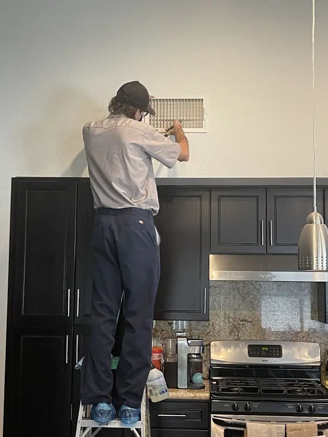Technician inspecting an air vent during HVAC service in Temecula